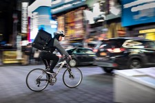 cyclist with food delivery backpack cycling through city