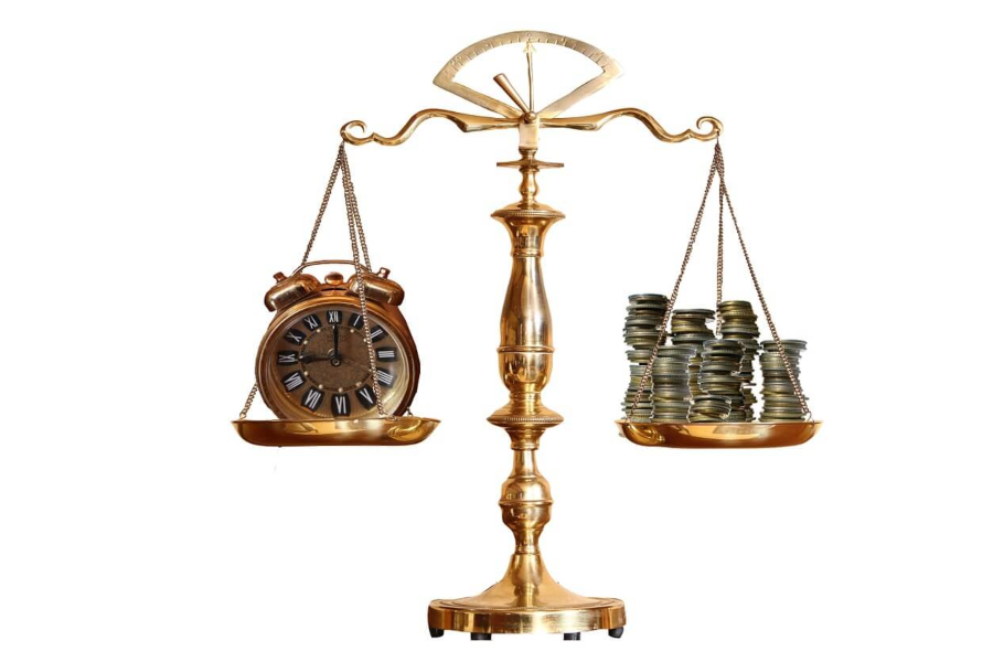 Scales with a clock on the left side and stacks of coins on the right side